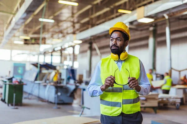 İnşaat alanında güvenlik kaskı ve gözlüklü Afro-Amerikan mimar.
