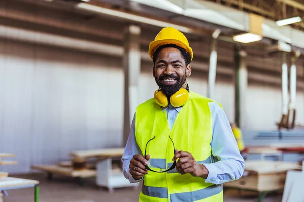 İnşaat alanında güvenlik kaskı ve gözlüklü Afro-Amerikan mimar.