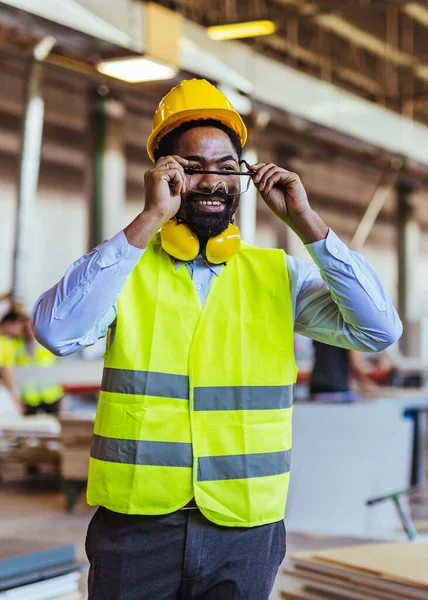 İnşaat alanında güvenlik kaskı ve gözlüklü Afro-Amerikan mimar.
