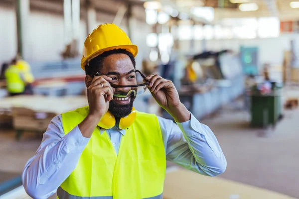 İnşaat alanında güvenlik kaskı ve gözlüklü Afro-Amerikan mimar.