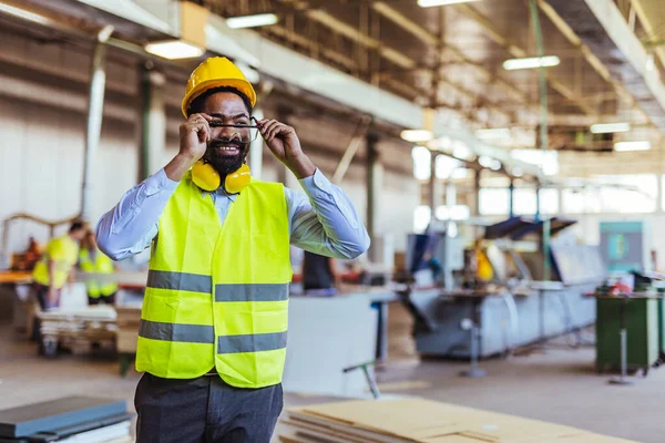 İnşaat alanında güvenlik kaskı ve gözlüklü Afro-Amerikan mimar.