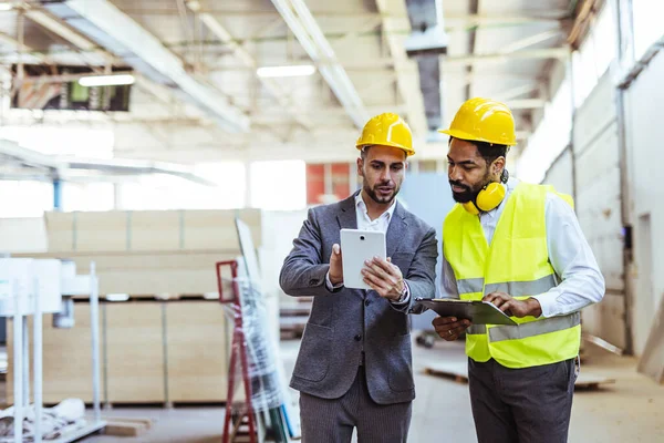 Depoda güvenlik ekipmanı takan iki profesyonel işçi