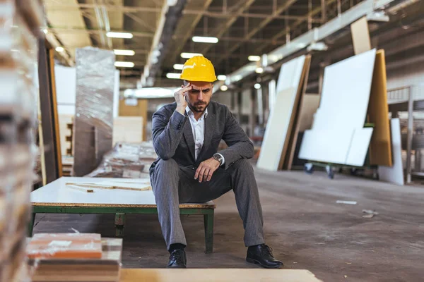 Sarı miğferi ve baş ağrısı olan genç bir mühendisin portresi.