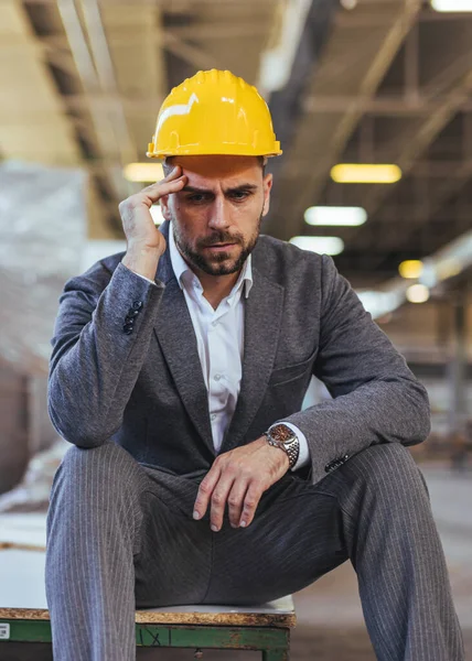 Sarı miğferi ve baş ağrısı olan genç bir mühendisin portresi.