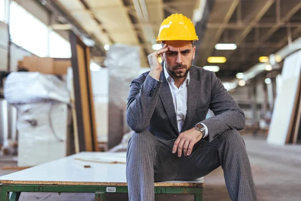 Sarı miğferi ve baş ağrısı olan genç bir mühendisin portresi.