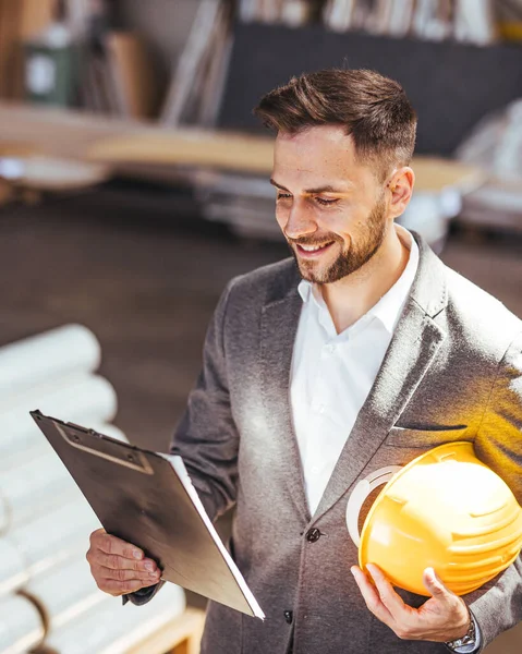 Kendine güvenen erkek mimarın portresi pano ve kasketi fabrikada.