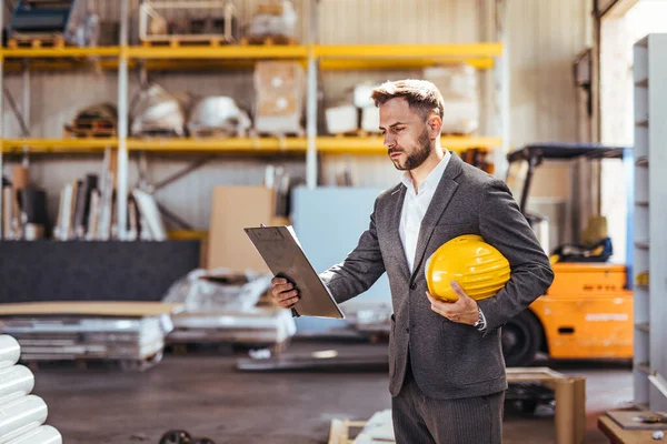 Kendine güvenen erkek mimarın portresi pano ve kasketi fabrikada.