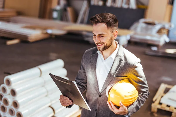 Kendine güvenen erkek mimarın portresi pano ve kasketi fabrikada.