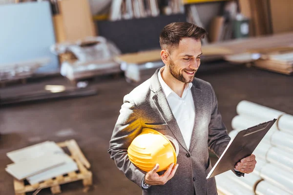 Kendine güvenen erkek mimarın portresi pano ve kasketi fabrikada.