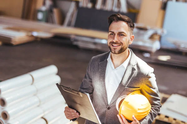 Kendine güvenen erkek mimarın portresi pano ve kasketi fabrikada.