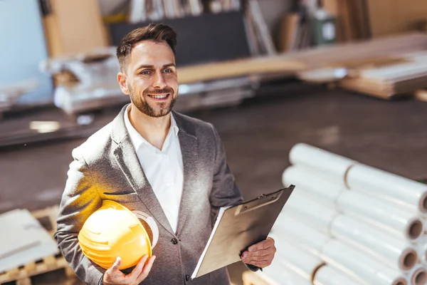 Kendine güvenen erkek mimarın portresi pano ve kasketi fabrikada.