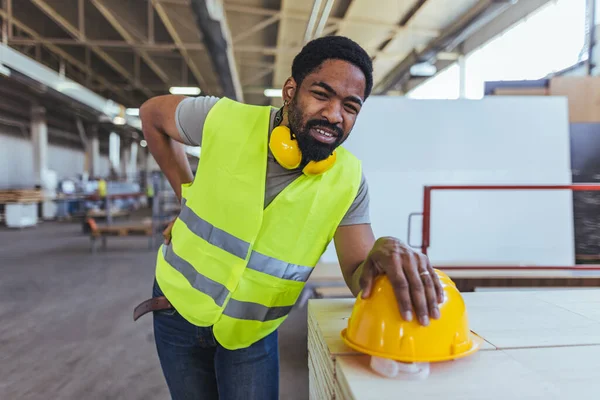 Depoda sarı kasklı ve sırt ağrısı olan Afro-Amerikan erkek mühendis.