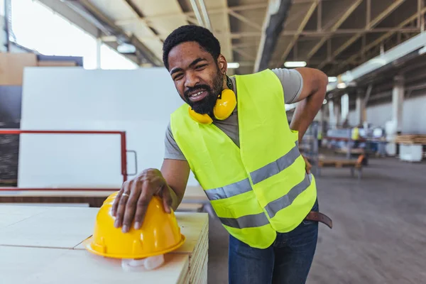 Depoda sarı kasklı ve sırt ağrısı olan Afro-Amerikan erkek mühendis.