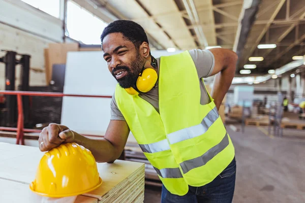 Depoda sarı kasklı ve sırt ağrısı olan Afro-Amerikan erkek mühendis.