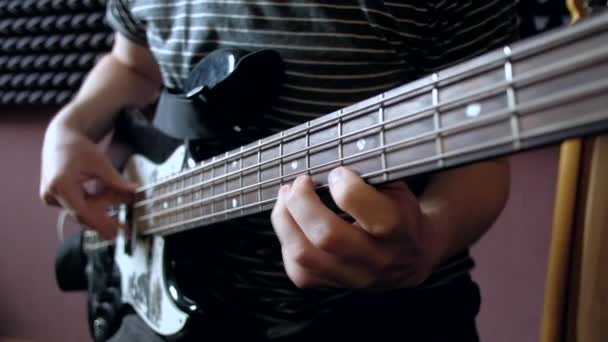 Музыкант играет на бас-гитаре в студии . — стоковое видео
