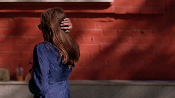 Girl in sunglasses walking down the street with a flower. — Stock Video