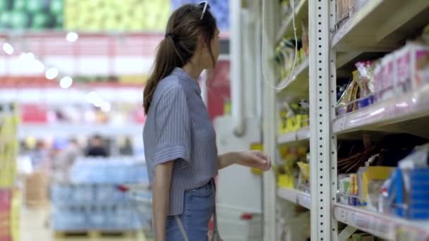 Mulher na loja de compras com uma cesta de supermercado — Vídeo de Stock