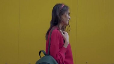 Sarı duvar boyunca yürüyen neşeli kadın