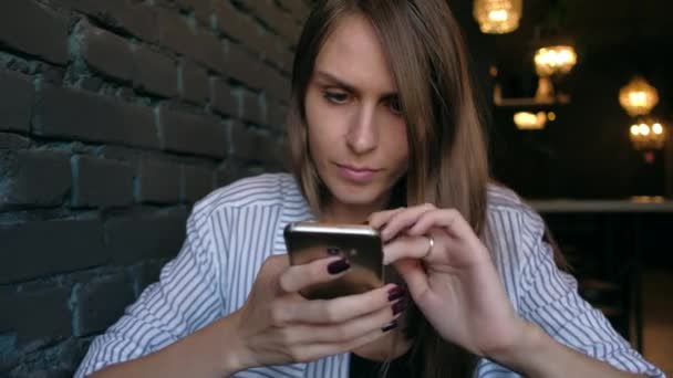 Όμορφη γυναίκα χρησιμοποιώντας smartphone και πίνοντας τον καφέ στην καφετέρια. — Αρχείο Βίντεο