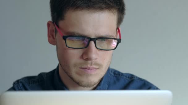 Mannen i glasögon arbetar på laptop på vit bakgrund. — Stockvideo