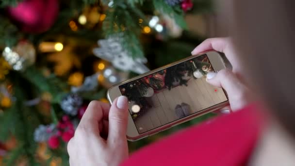Жінка фотографує на смартфоні ялинку вдома . — стокове відео