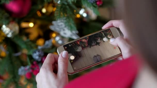 Mujer fotografiando en el árbol de Navidad smartphone en casa . — Vídeo de stock