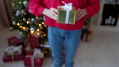 Yakın çekim - kız kırmızı tişört ve kot vermek Noel hediye kutusu.