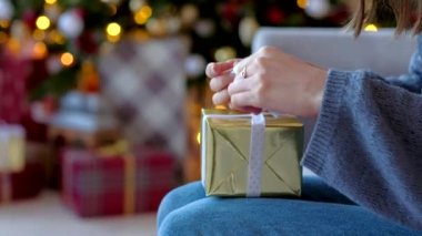 Yakın çekim - kadının elleri bir hediye ile altın bir kutu üzerinde bir yay bağlama bir yeni yıl sürpriz hazırlar. Xmas 2019.