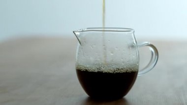 Barista taze yapılmış kahve şeffaf bir kupa dökülen..