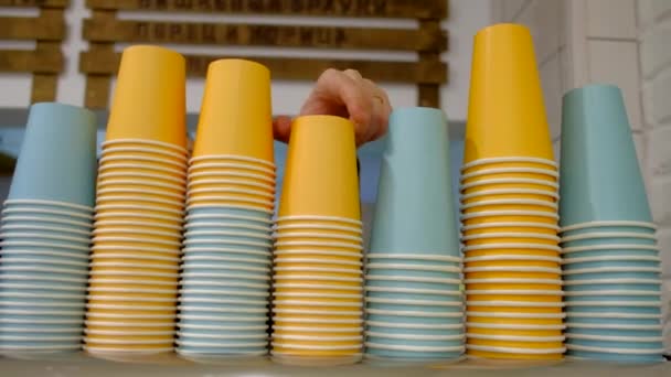 巴里斯塔男人在咖啡馆里拿着彩色纸杯 大量五颜六色的饮水纸咖啡杯成堆 堆叠的一次性咖啡杯 — 图库视频影像