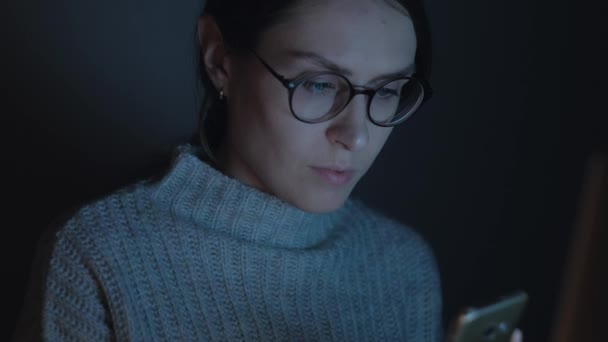 チルトアップ ショット - 美しい女性は、夜のスマート フォンを使用します。クローズ アップ。4 k. — ストック動画