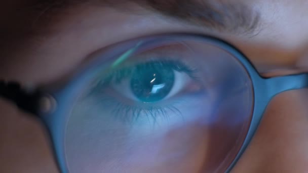Extreme close-up van oog van vrouw in glazen werken bij laptop's nachts. 4k. — Stockvideo