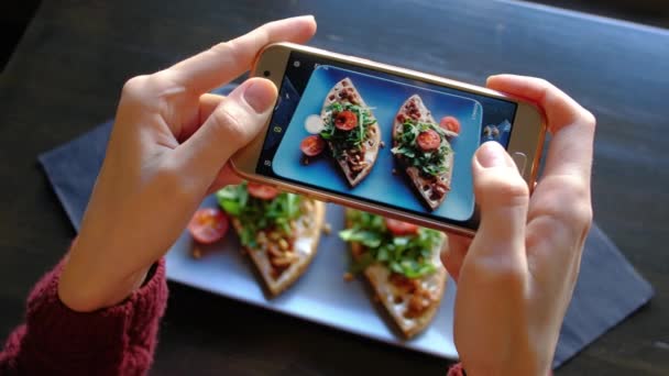 Vrouwelijke handen fotograferen smakelijk voedsel door smartphone in het restaurant. — Stockvideo
