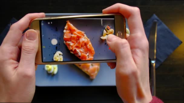 Vrouwelijke handen fotograferen smakelijk voedsel door smartphone in het restaurant. — Stockvideo