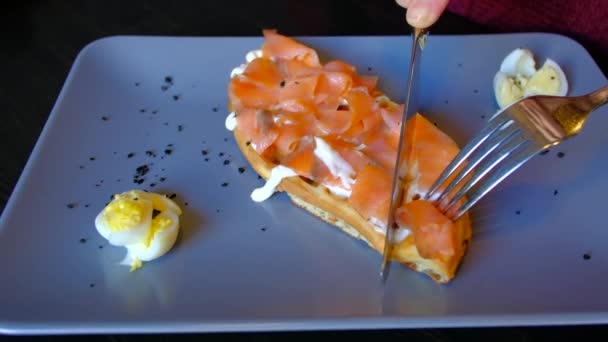 Крупним планом - жінка їсть вафлі з червоною рибою в кафе . — стокове відео