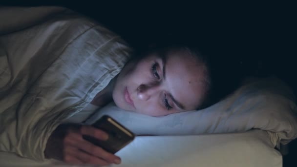 Γυναίκα χρήση του κινητού τηλεφώνου και ξαπλωμένη στο κρεβάτι τη νύχτα — Αρχείο Βίντεο