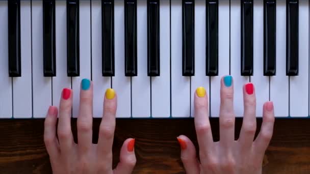 Молодая позитивная девушка с красивыми руками и цветным маникюром играет на пианино . — стоковое видео