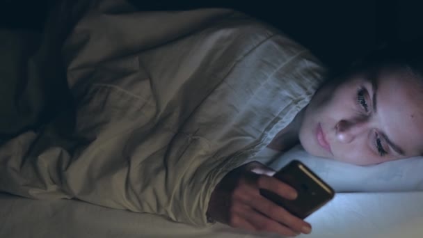 Frau benutzt Handy und liegt nachts im Bett — Stockvideo