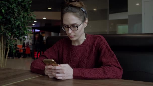 Carino femminile utilizzando smartphone nel caffè . — Video Stock