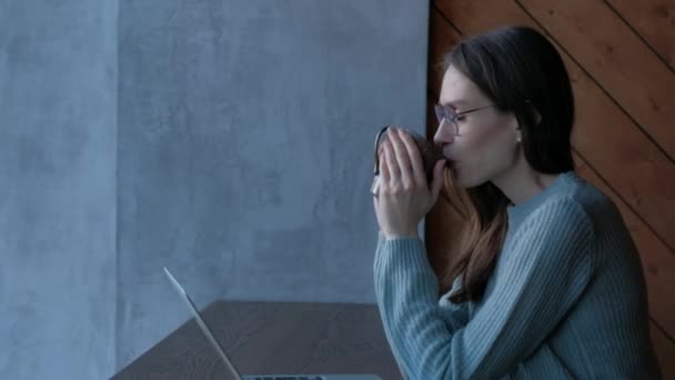 Vrouw met een goed humeur zit in café en drinkt koffie geniet van de smaak. — Stockvideo