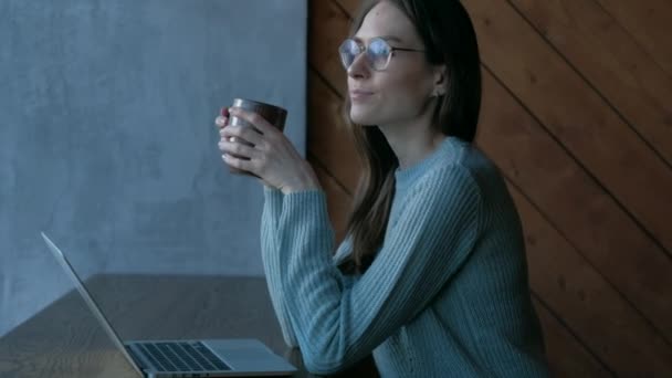 Linda chica con el ordenador portátil en la cafetería mirando en la ventana, bebidas café disfrutar del sabor . — Vídeo de stock