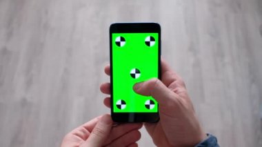 Evde yeşil ekranlı akıllı telefon kullanan erkek 