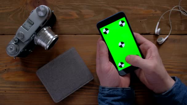 Fotógrafo usando smartphone con pantalla verde en mesa de madera . — Vídeo de stock