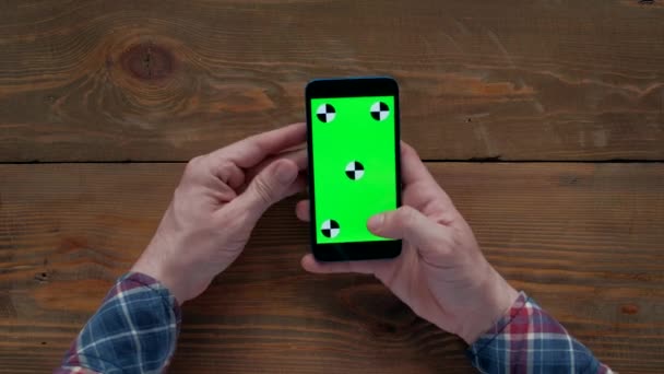 男子使用智能手机与绿色屏幕在木桌上. — 图库视频影像
