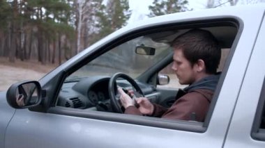 Genç bir adam akıllı telefon kullanmak, araba kabinde oturan.