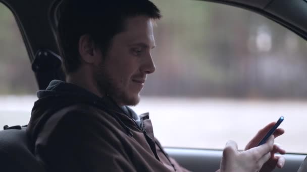 El conductor utiliza el teléfono inteligente, sentado en el coche . — Vídeos de Stock