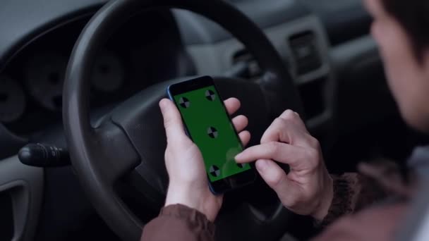 Conducteur masculin utilisant un smartphone avec écran vert dans la voiture .