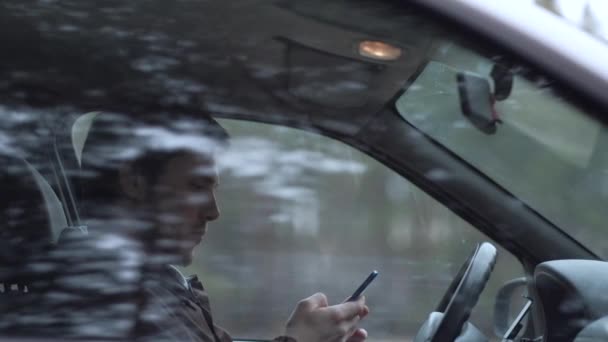 Οδηγός χρησιμοποιούν smartphone, κάθεται στο αυτοκίνητο. — Αρχείο Βίντεο