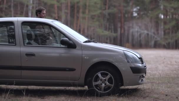 Az ember kijutni a kocsiból, és megnyitja a motorháztető. — Stock videók