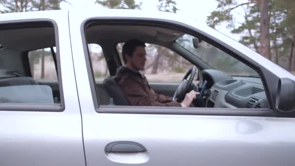 ヨーロッパの男性は、車のキャビンに座って、スマートフォンを使用します. — ストック動画